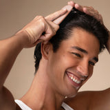 KITSCH Scalp Renewal Brush in Terracotta — lifestyle shot — smiling model massaging his scalp with the brush — gentle circular massage helps work scalp oil in for a relaxing pampering ritual