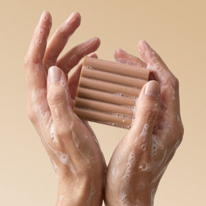 Close-up of hands holding Kitsch Warm Sugar Body Wash Bar with rich sudsy lather and bubbles