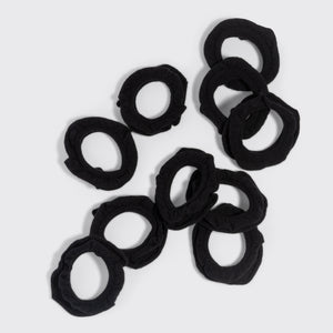 Black petal hair elastics scattered on a grey background