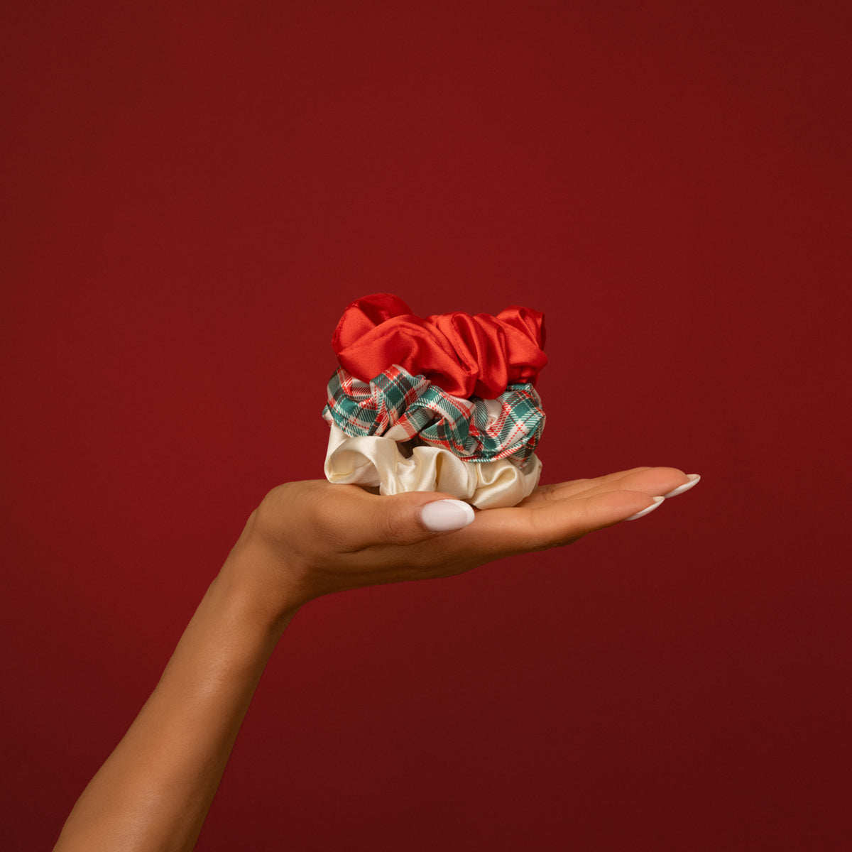 KITSCH Red & Gold Holiday Scrunchies 3pc Set — open palm holding all three scrunchies against a deep red backdrop — Soft fabric provides a gentle hold — cozy holiday days