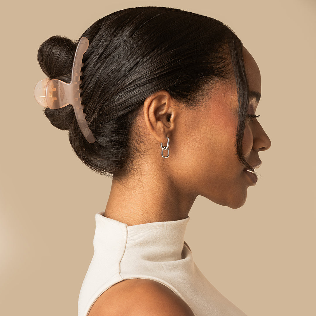 Model wearing the kitsch translucent Soft Pink Arched Claw Clip - Large securing dark hair in a sleek updo
