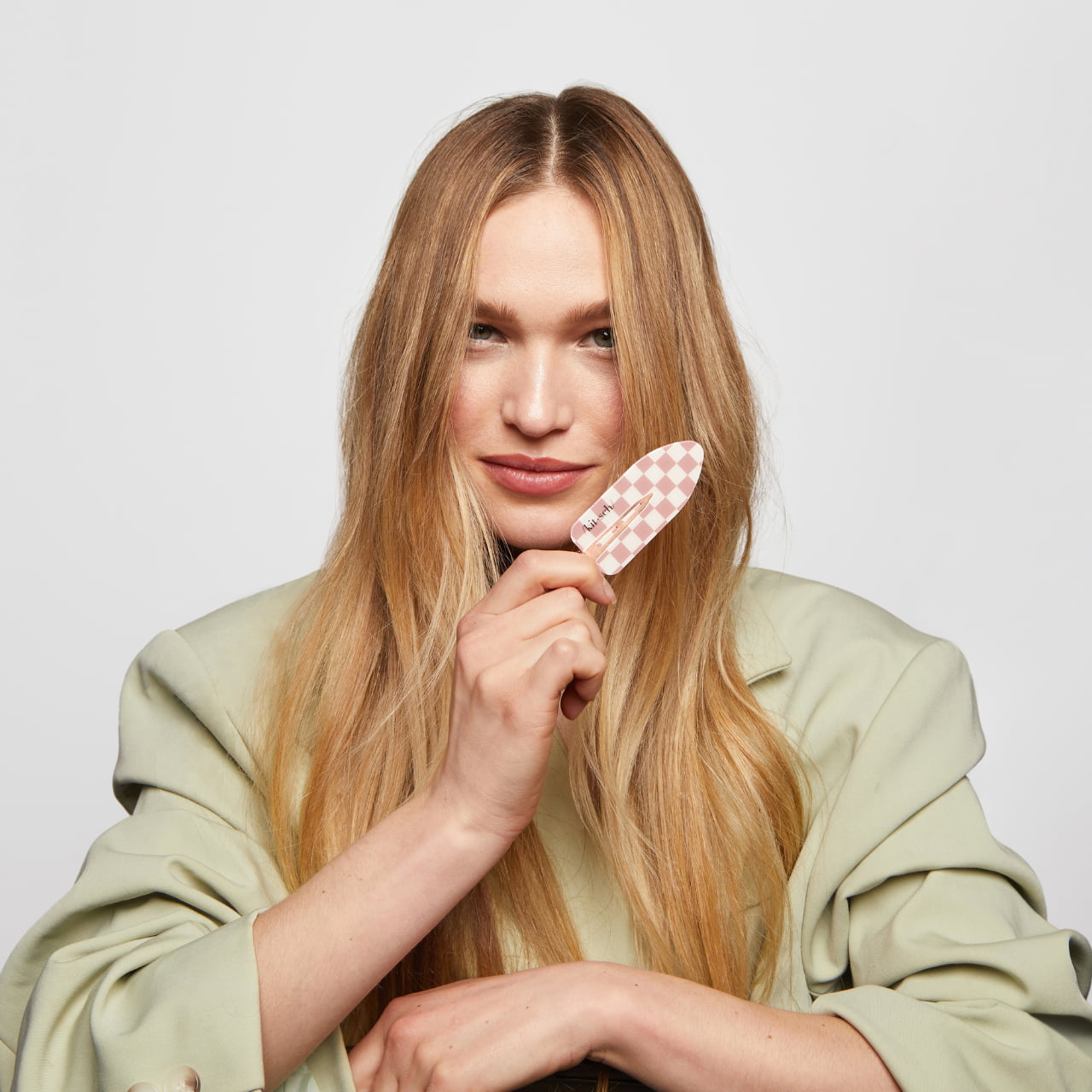 XL Terracotta Checker Creaseless Clips 2pc Set- model with long blonde hair holds a small pink and white checkered hair clip near her face, against a plain gray background.
